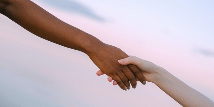 Two people reaching out and holding hands